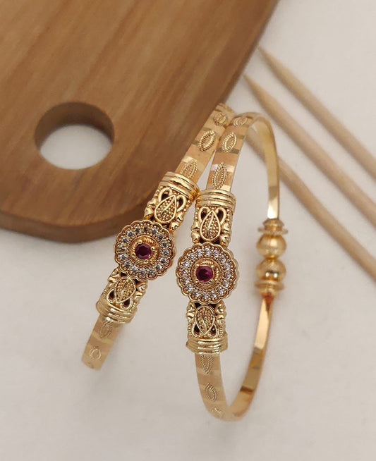 Delicate and elegant gold bangles with a floral design and a hint of pink