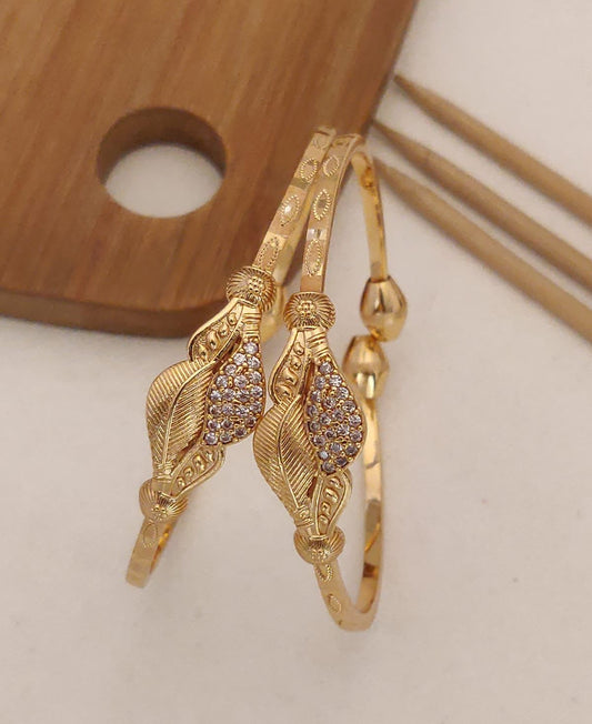 Delicate and elegant gold bangles with intricate leaf design and sparkling white stones. Perfect for any occasion!